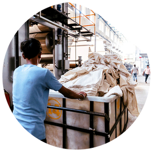 Eine Person schiebt einen Wagen voller Leinenstoff durch eine Verarbeitungshalle